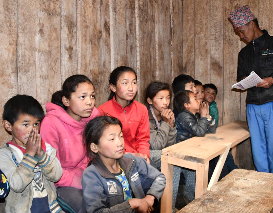 Mehrere nepalesische Kinder mit einem Erwachsenen beim Gebet
