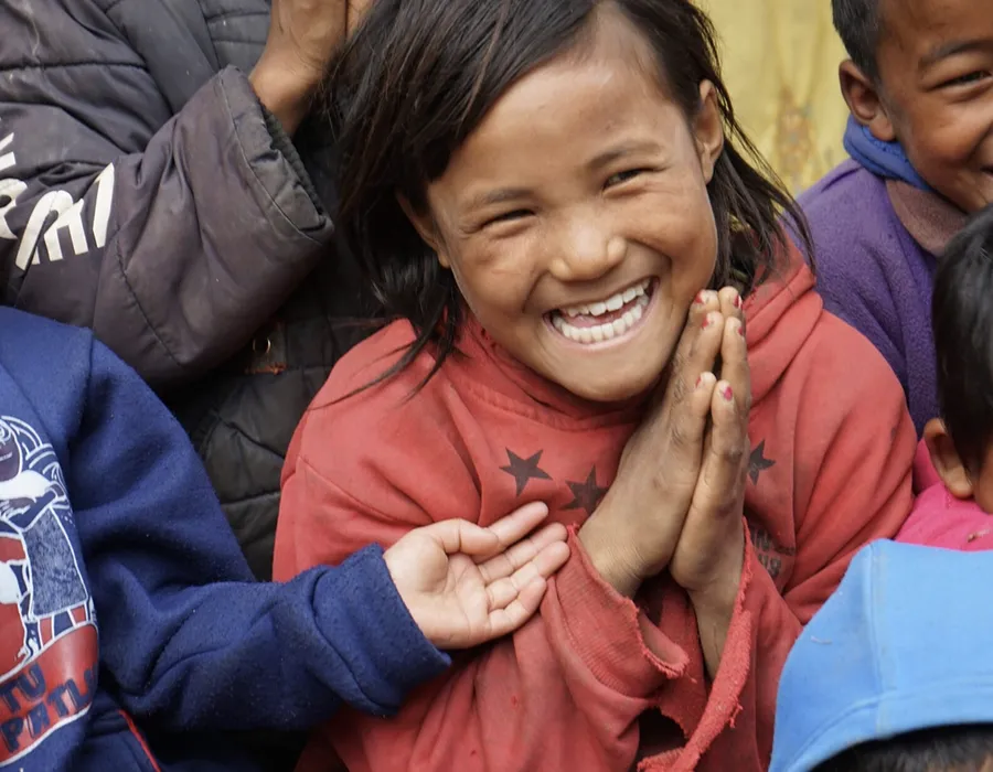 Mehrere freudig lachende nepalesische Kinder in zerschlissener Kleidung