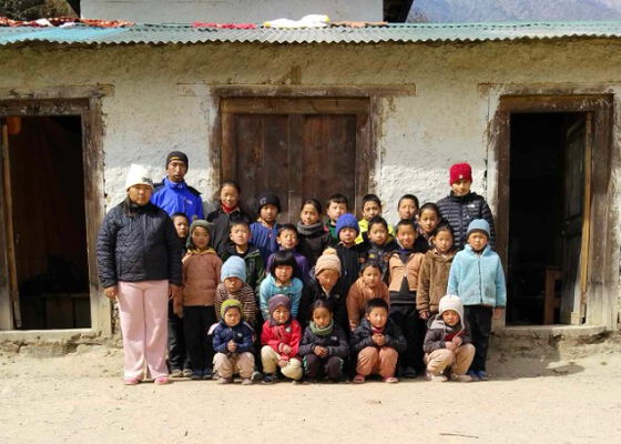Klassenfoto - nepalesische Kinder stehen vor dem alten Schulgebäude mit Wellblechdach und abbröckelndem Putz in Chumelu.