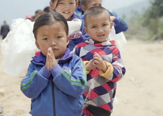 Mehrere nepalesiche Kinder stehen hintereinander im Freien und blicken in die Kamera.