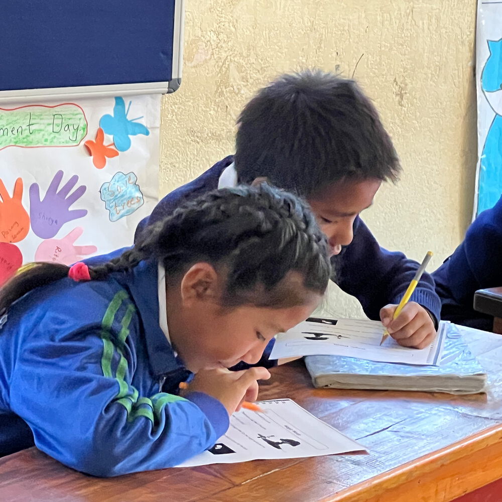 Zwei nepalesische Kinder erledigen konzentriert Schulaufgaben